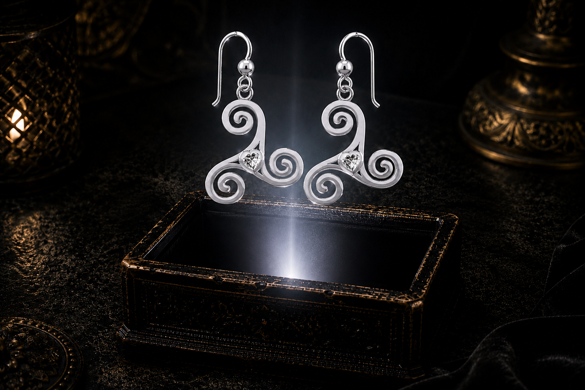 Sterling silver Celtic triskele spiral earrings with cubic zirconia heart gemstones floating above a glowing ornate jewelry box in a dark luxury setting
