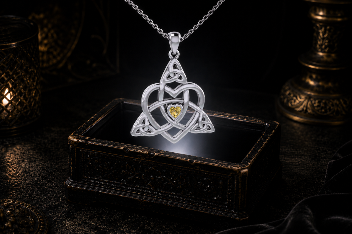 Citrine Celtic Trinity heart pendant on a sterling silver cable chain suspended above an illuminated antique jewelry box