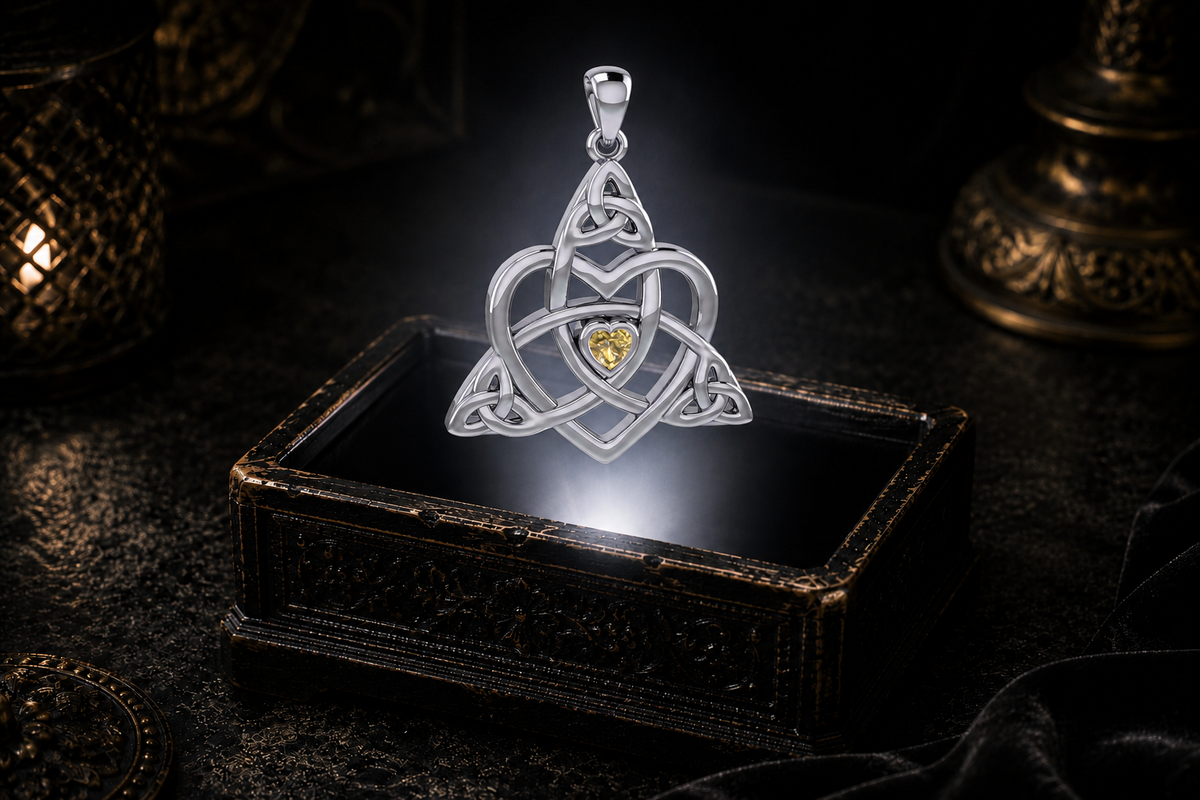 Sterling silver Celtic Trinity heart pendant with a heart-shaped citrine floating above an ornate antique jewelry box in a dark setting