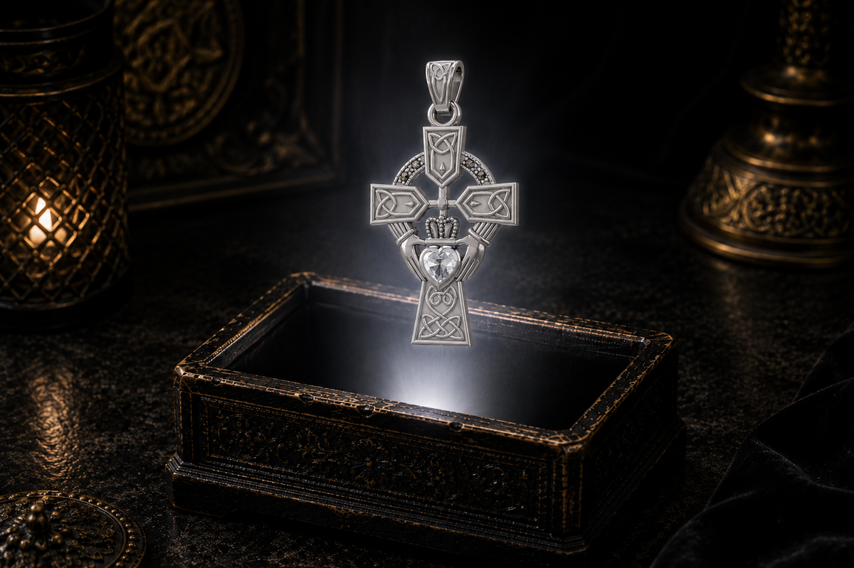 14K white gold Claddagh Celtic Cross pendant with a heart-shaped faceted cubic zirconia gemstone, flowing Celtic knotwork, and marcasite accent stones floating above an ornate jewelry box in a refined dark luxury setting with warm candlelight, cinematic lighting, and a mystical atmosphere.