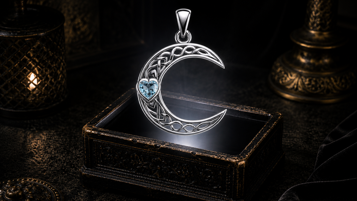 14K white gold crescent moon pendant featuring a heart-shaped blue topaz gemstone and intricate Celtic knotwork floating above an ornate jewelry box in a dark cinematic luxury setting illuminated by a mystical glow.