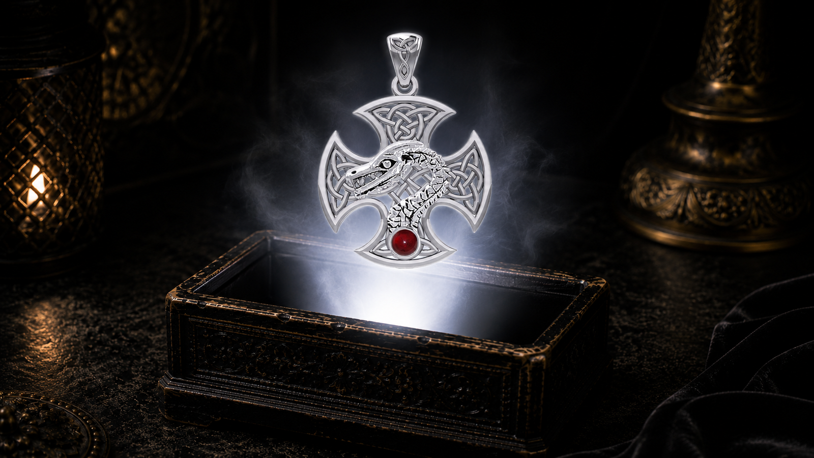 Sterling silver Dragon Serpent Celtic Cross pendant with garnet gemstone floating above an ornate black jewelry box illuminated by soft white light in a dark luxurious Celtic-inspired setting with candlelit ambiance.