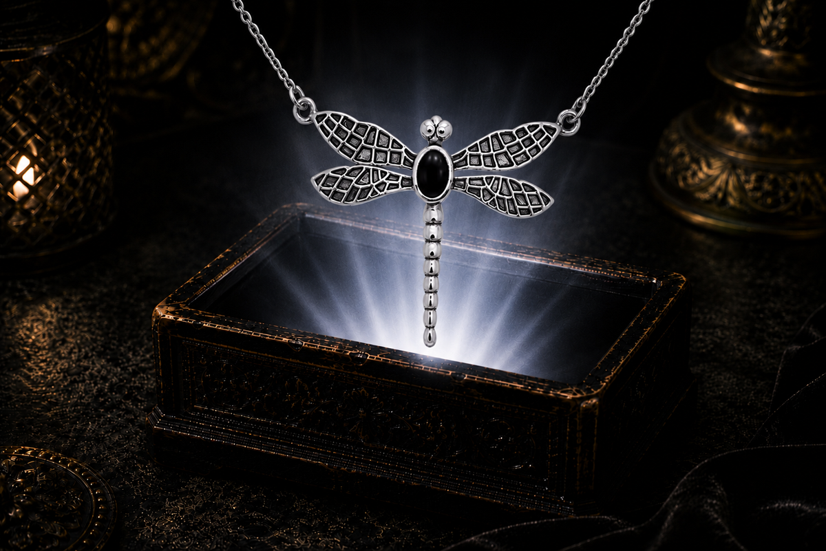Sterling silver dragonfly necklace with black onyx gemstone floating above a luminous ornate jewelry box in a dark cinematic setting