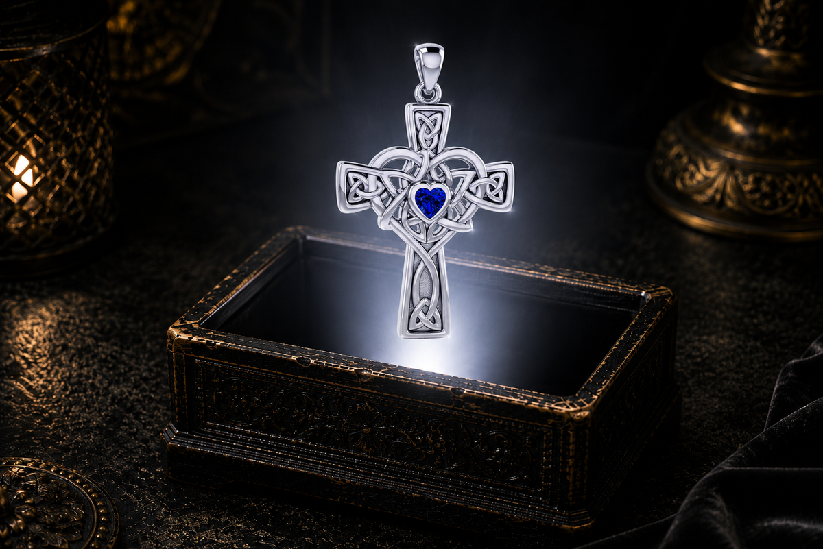 Sterling silver Celtic Heart Cross pendant with a heart-shaped Created Sapphire gemstone hovering over an ornate jewelry box in a dramatic illuminated scene.