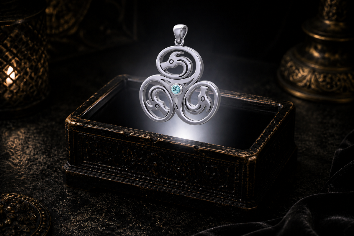 Sterling silver Celtic triple dragon necklace with a blue topaz gemstone displayed against a dark cinematic jewelry backdrop.