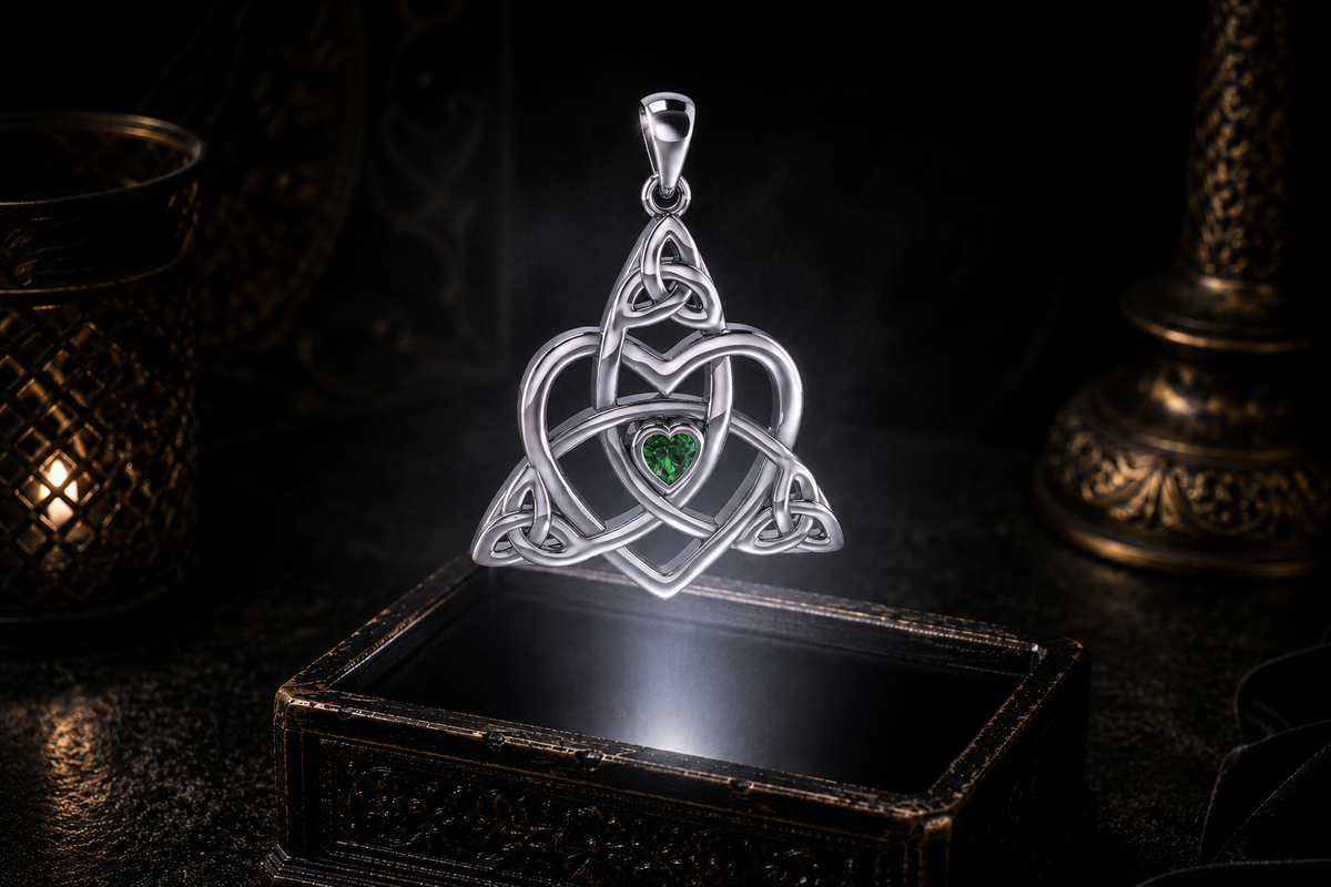 Heart-shaped emerald framed by sterling silver Celtic Trinity knotwork, hovering above an antique jewelry box against a dark backdrop