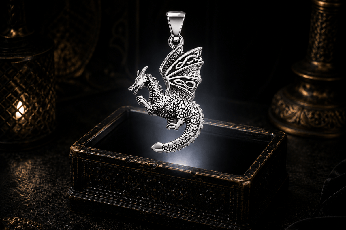Sterling silver flying dragon pendant with detailed scales, raised forelegs, curled tail, a Trinity knot in the upper wing, and Celtic knotwork below.