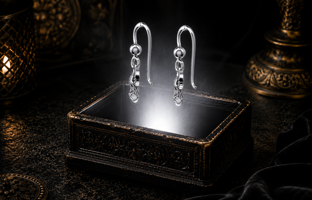 Highland cow earrings in Sterling Silver with Celtic Trinity Knot details side-view suspended above an antique luxury jewelry box illuminated by a soft white beam in a cinematic dark setting.