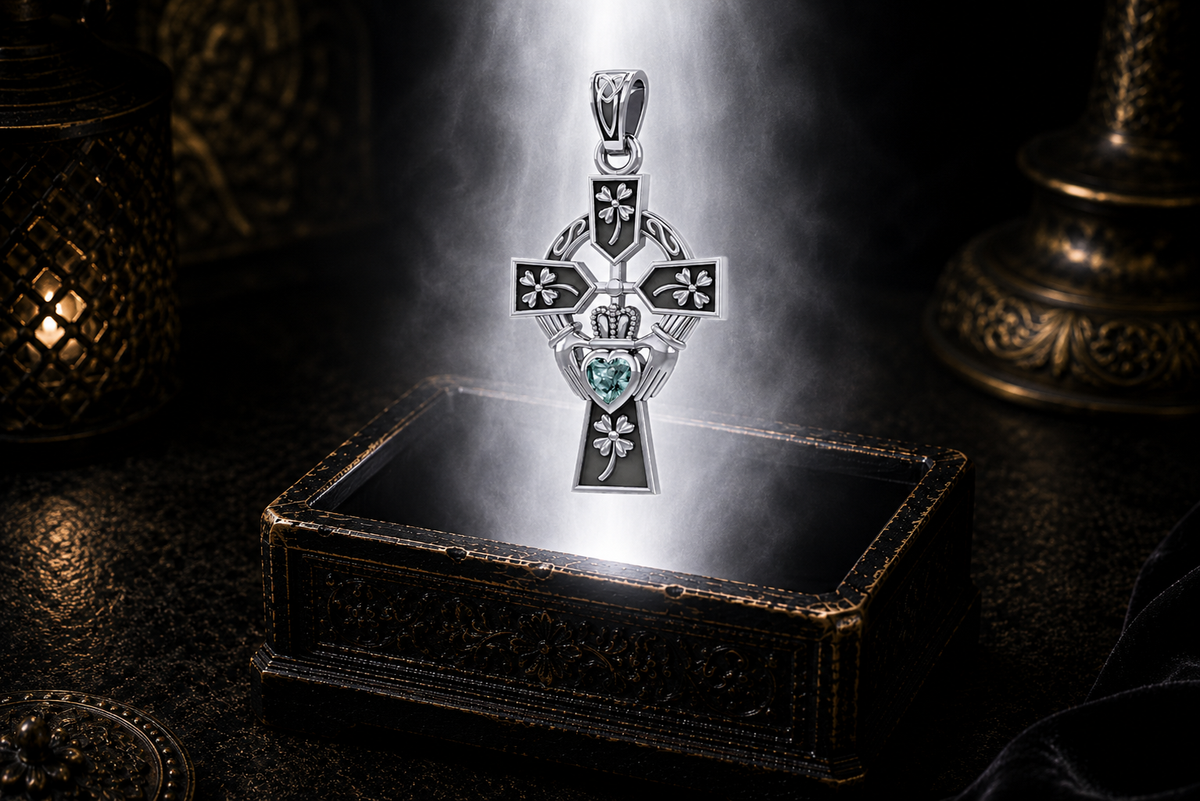 Sterling silver Irish Claddagh Cross pendant with Four Leaf heart design and blue topaz heart gemstone displayed above a luminous jewelry chest in a cinematic shadowed setting.