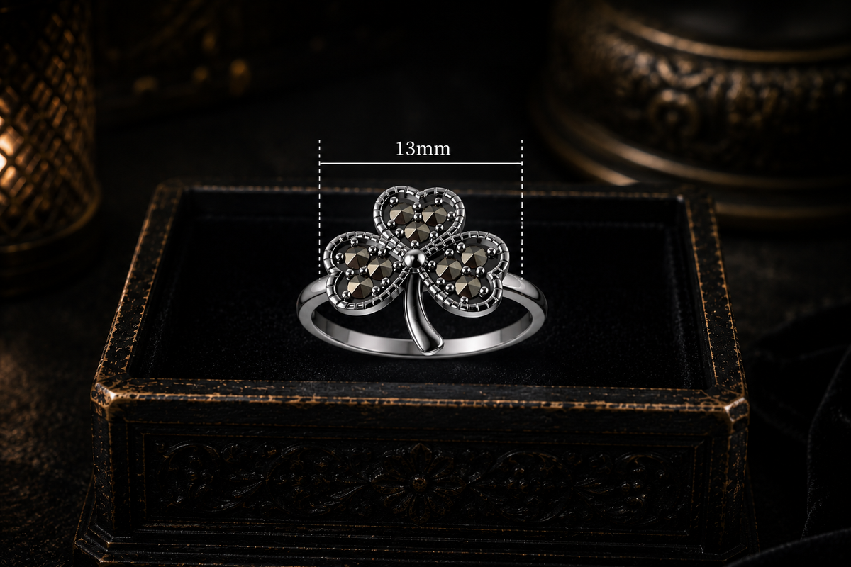 Lucky sterling silver Celtic shamrock ring with marcasite displayed on a dark antique jewelry box with 13mm size measurement in a mystical candlelit setting