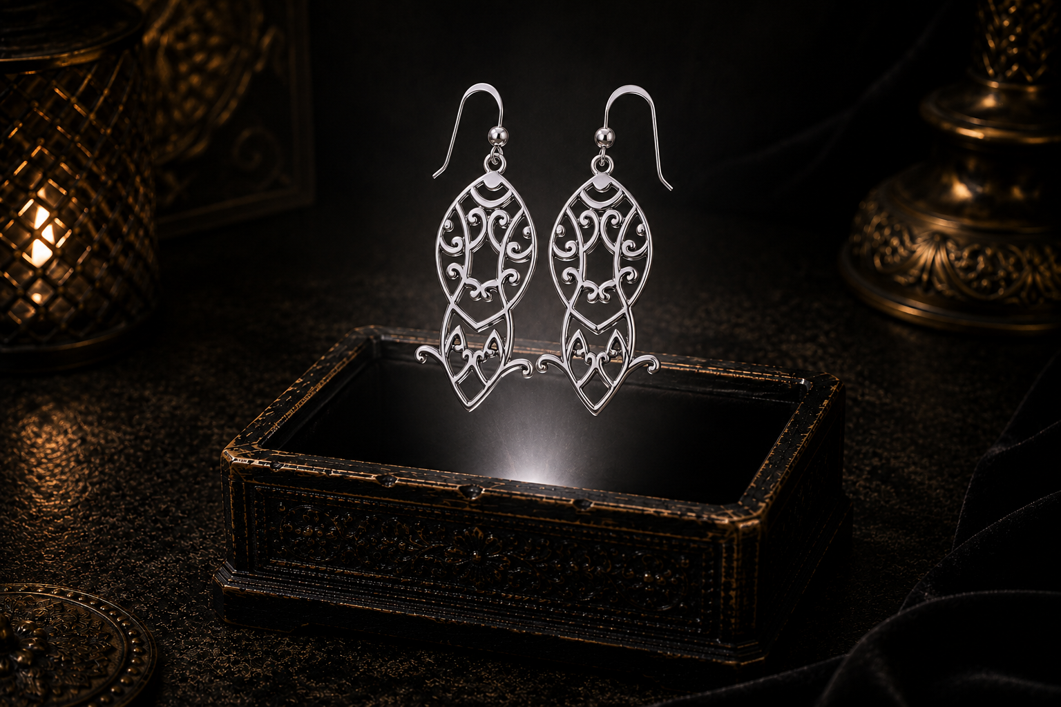 Sterling silver Maori Celtic drop earrings featuring intricate Celtic knotwork and spiral-inspired motifs floating above an ornate jewelry box in a dark luxury setting illuminated by soft glowing light.