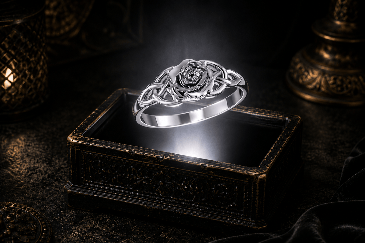 Sterling silver rose ring with open Celtic Trinity knots suspended above an antique jewelry box in a dramatic luxury setting illuminated by a neutral white beam of light.