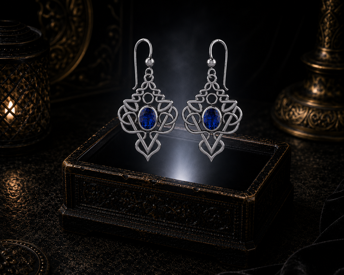 Sterling silver Celtic filigree knot drop earrings with sapphire gemstones floating above a glowing ornate jewelry box in a dark luxury setting