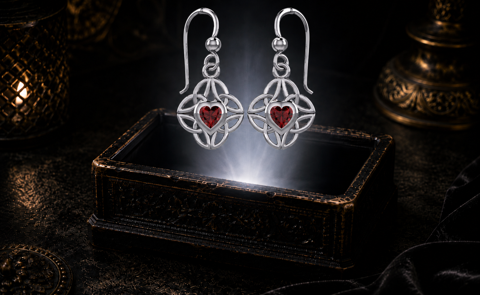 Sterling silver Celtic heart earrings with four interconnected Triquetra knots and garnet gemstones floating above an ornate jewelry box in a dark luxury jewelry display with mystical illumination.
