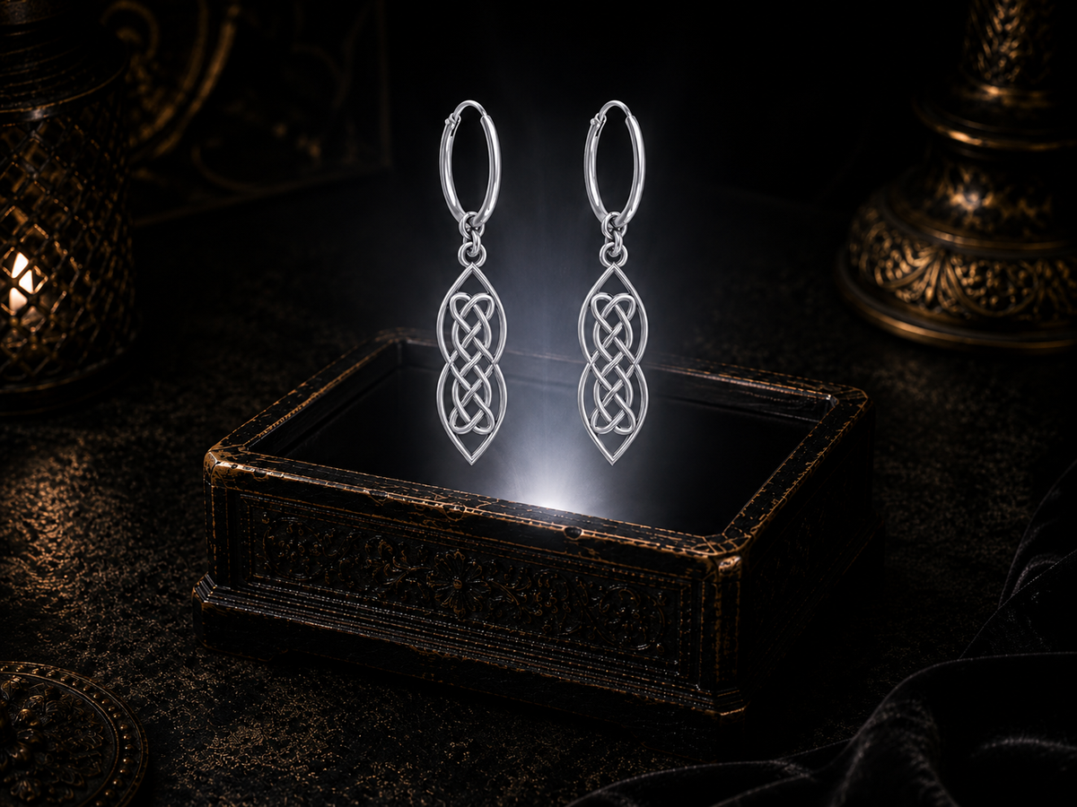 Sterling silver Celtic knot dangle hoop earrings floating above a glowing ornate jewelry box in a dark luxury setting