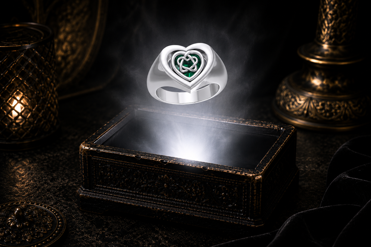 Sterling silver reversible Celtic heart flip ring displaying an intricate Trinity Knot over emerald glass, photographed in a luxury dark jewelry box with a glowing white light and cinematic atmosphere.