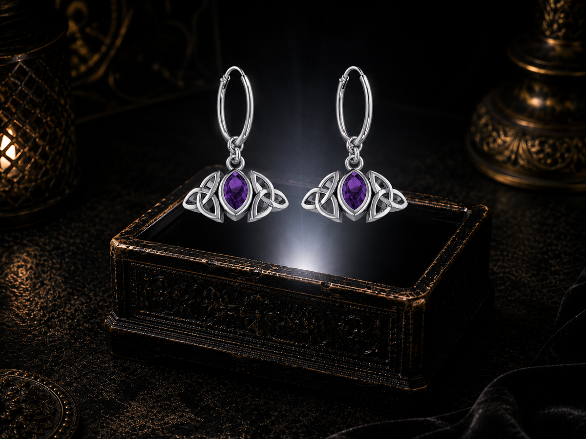 Sterling silver Triquetra charm hoop earrings with amethyst gemstones floating above a glowing ornate jewelry box in a dark luxury setting
