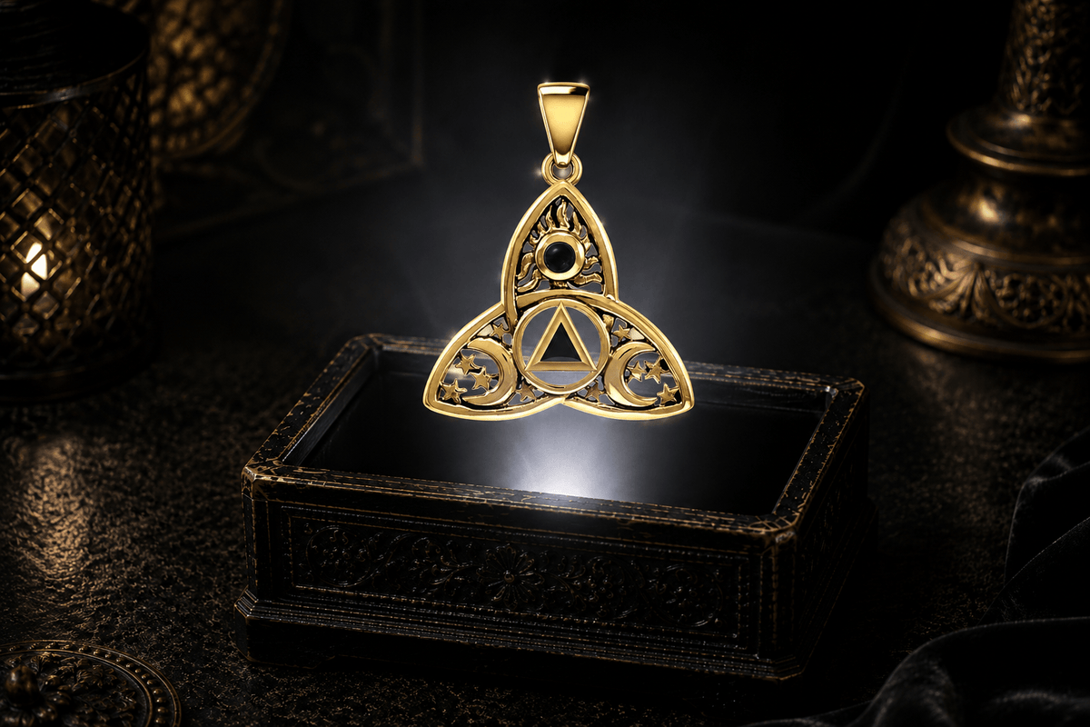 Yellow gold Celtic Trinity Knot pendant with black onyx, crescent moons and stars suspended above an antique jewelry box