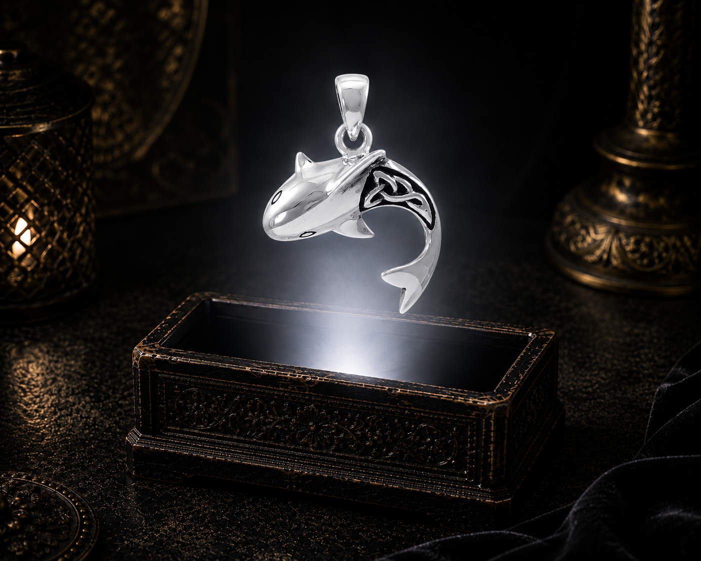 Sterling silver swimming shark pendant with Celtic-inspired detailing floating above an ornate jewelry box in a dark cinematic luxury setting illuminated by soft mystical light.