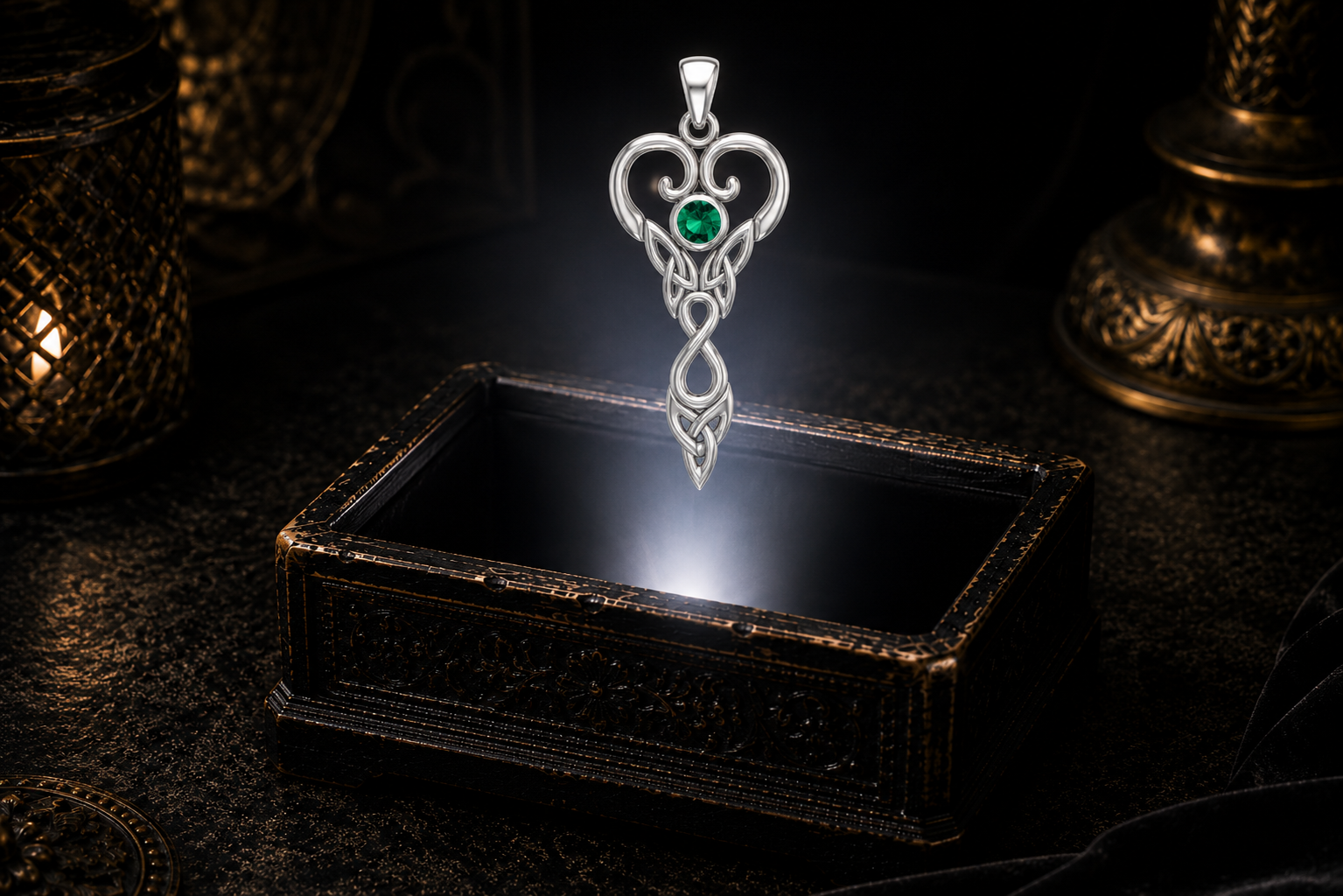 Taurus white gold goddess pendant with emerald glass suspended over an ornate black jewelry box in a dark luxury setting