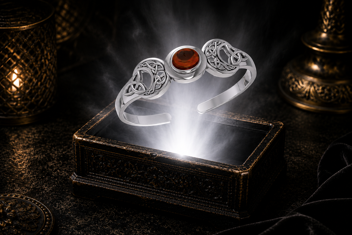 Sterling silver Triple Moon Celtic knot cuff bracelet with garnet gemstone floating above an ornate jewelry box illuminated by soft white light in a dark luxury setting with mystical lunar symbolism and cinematic elegance.