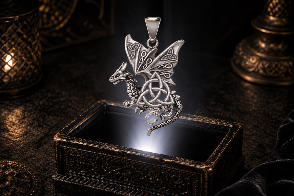 14K white gold winged dragon pendant with open Celtic knotwork, a central Triquetra, scaled body, curling tail and round gemstone drop.