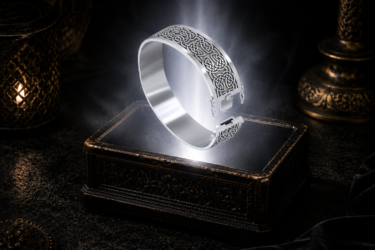 Wide sterling silver Celtic knotwork hinged bangle bracelet floating above an ornate black jewelry box illuminated by soft white light in a dark luxury setting with refined Celtic elegance and cinematic atmosphere.