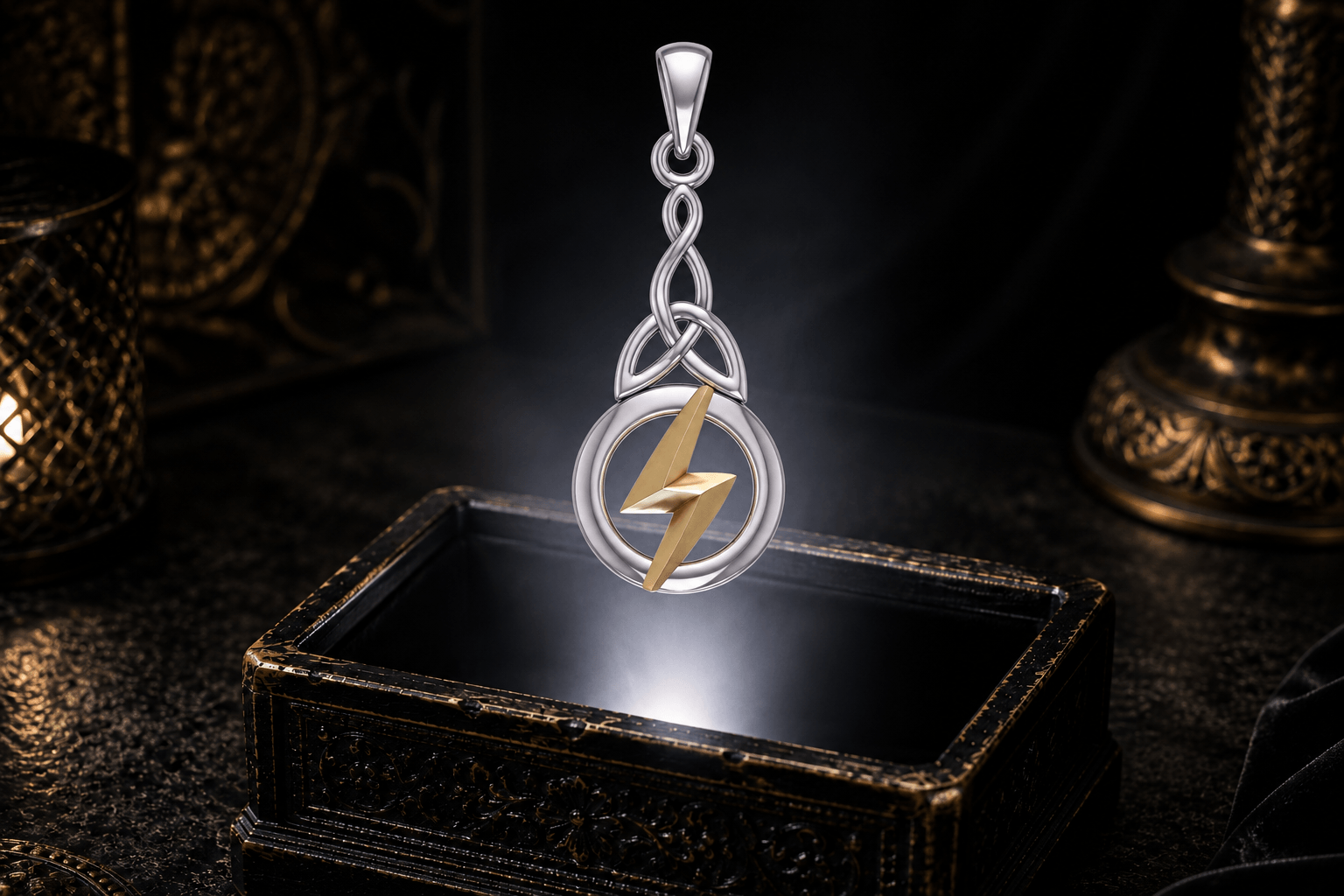 Sterling silver Celtic knot pendant with a gold Zeus lightning bolt hovering above an ornate black jewelry box in a neutral white beam.